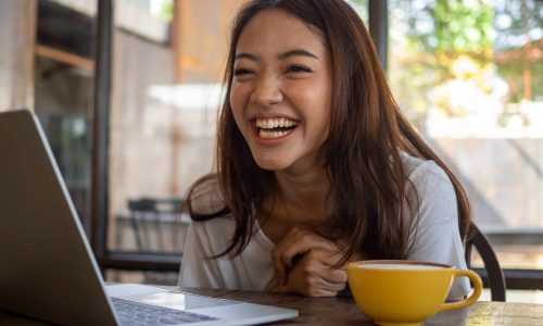 A Beautiful Asian Woman Laughed Happily While Sitting In A Cafe.